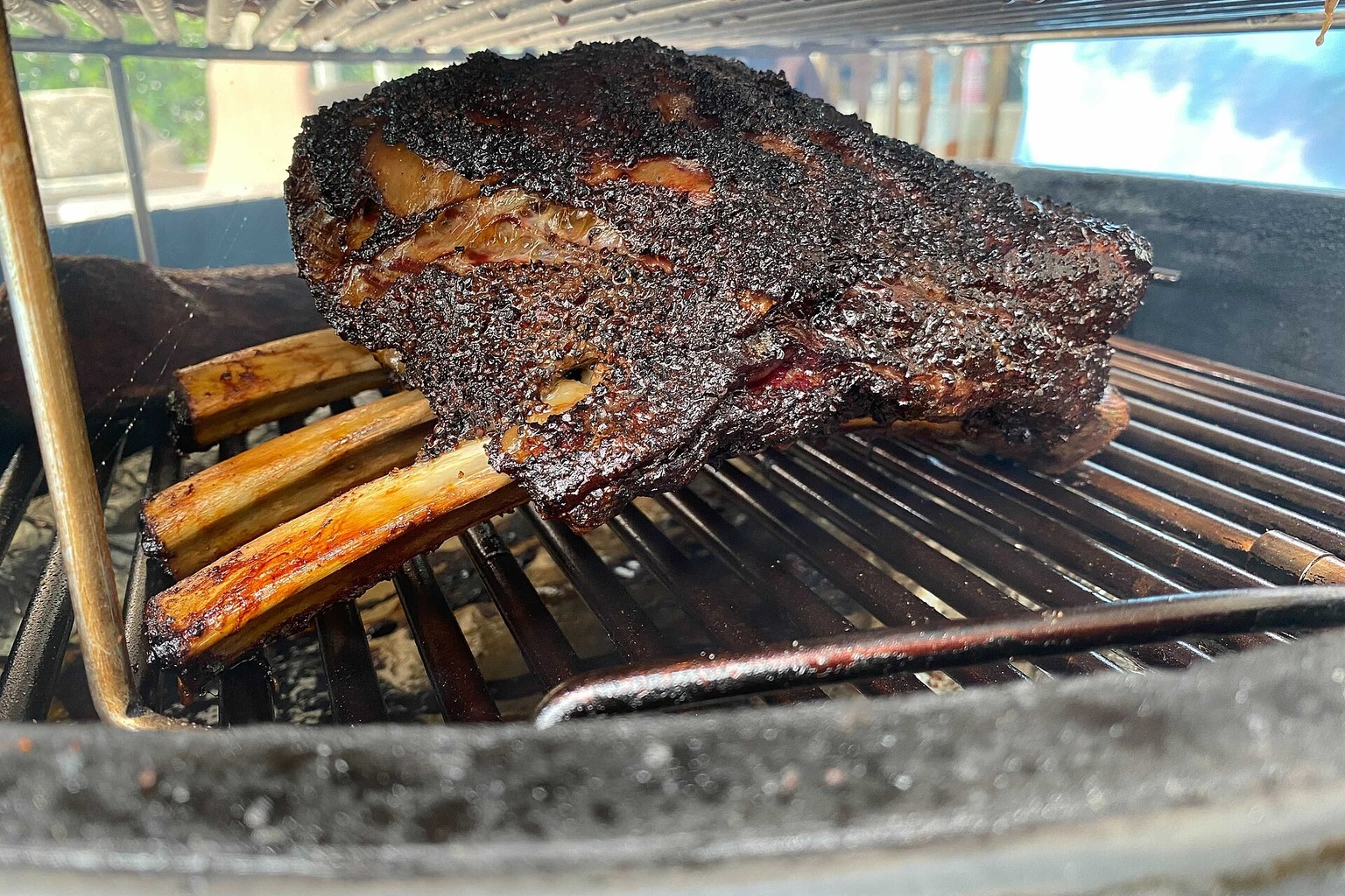 Beef ribs cooking on a smoker grill.