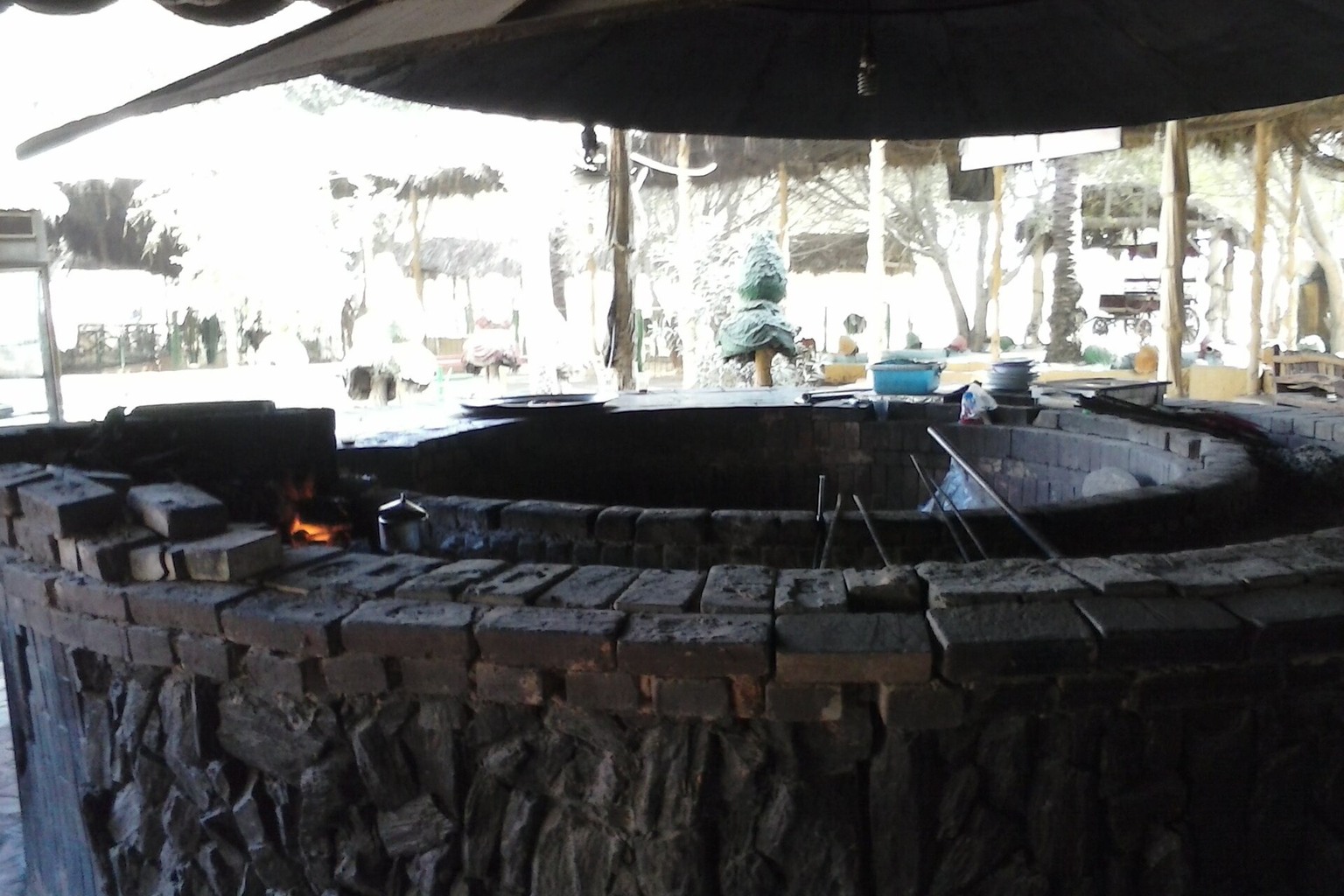 An outdoor cooking station with a large circular grill and cooking utensils.