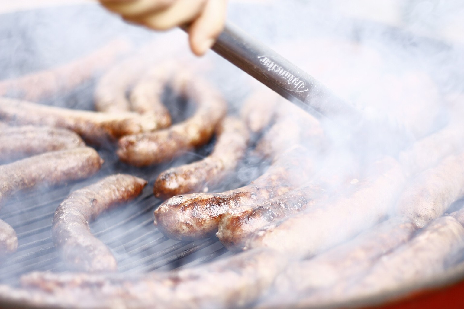 Sausages cooking on an outdoor grill.